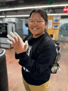 student holds up her hand against 3D printed hand